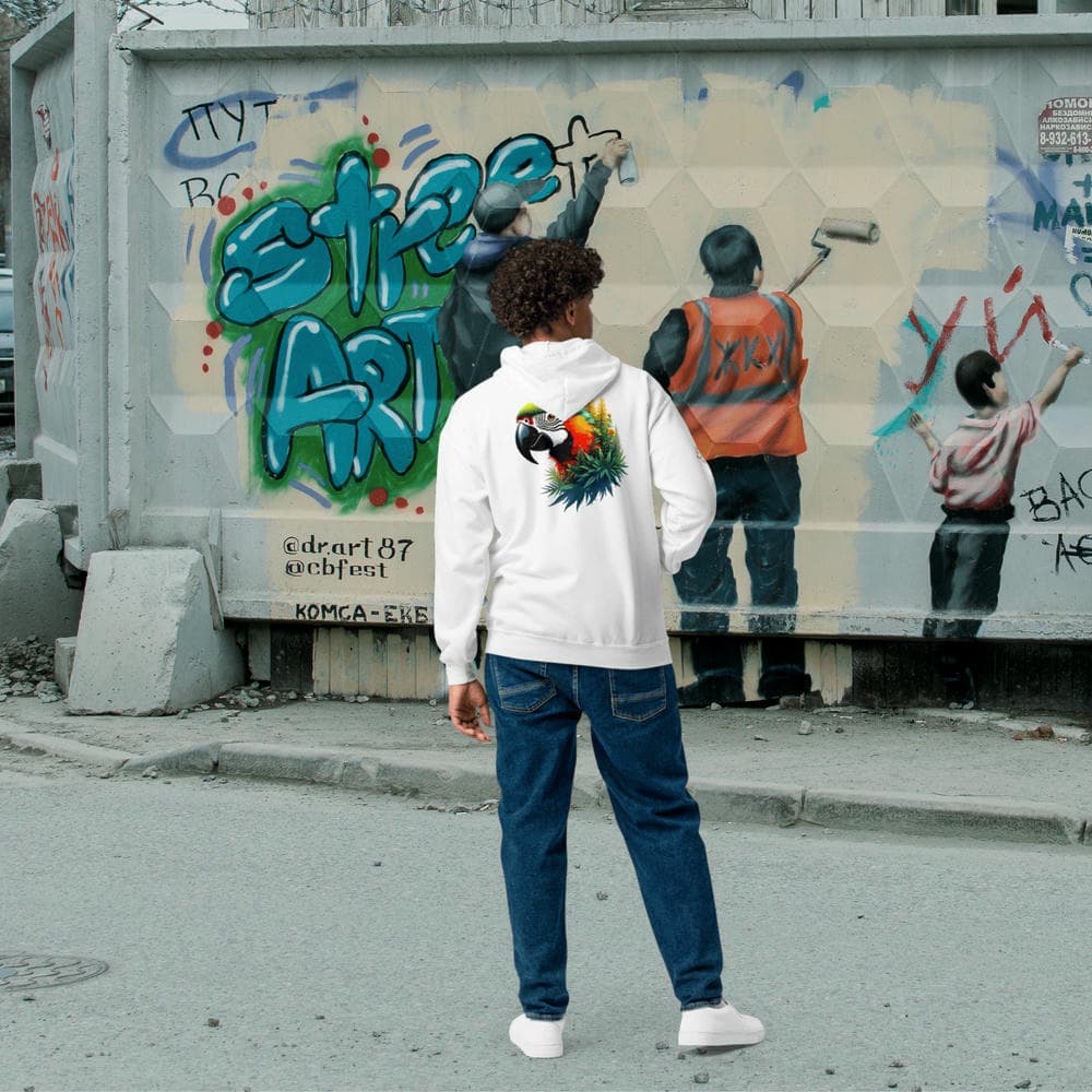 Jeune homme portant le Hoodie Zippé Alpha blanc avec le design Perroquet Ara devant un mur street art