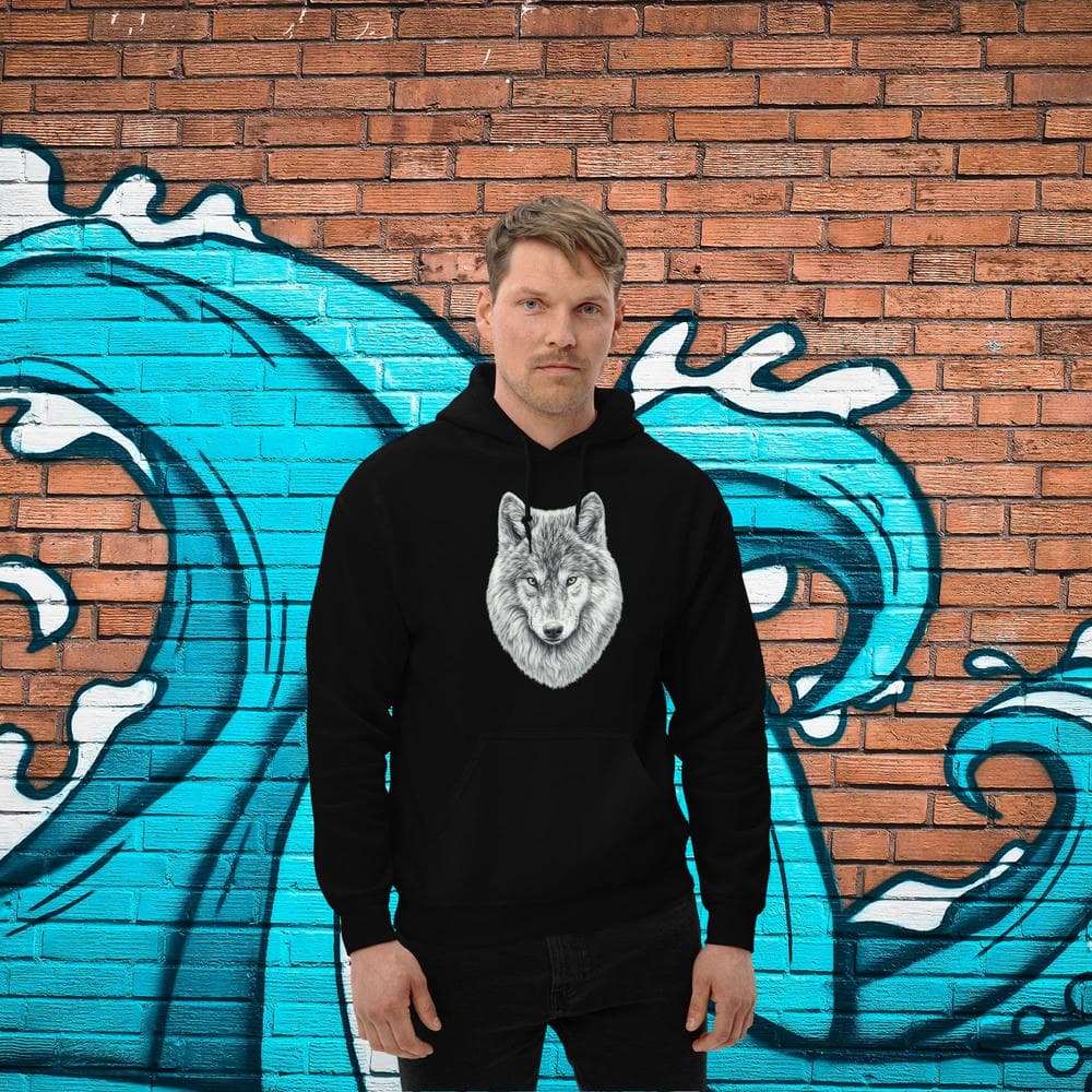 Vue de face d'un homme portant le Hoodie Essentiel noir Instinct Émeraude devant un mur de briques avec une fresque de vague bleue. Style urbain dynamique et design by Mister Felpatee pour un look Felpatee efficace et moderne.