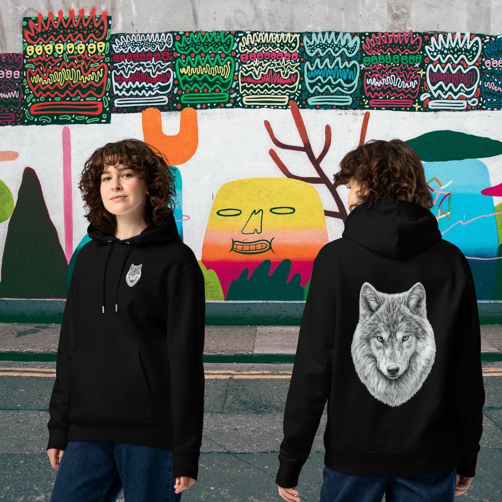 Vue de dos et de face d'un couple portant le Hoodie Prestige noir Instinct Émeraude devant un mur de graffitis urbain. Le Sceau de la Meute et le design artistique intégral marquent cette édition signature haut de gamme.